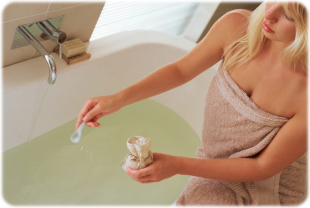 Woman sprinkling salt crystals into bath water